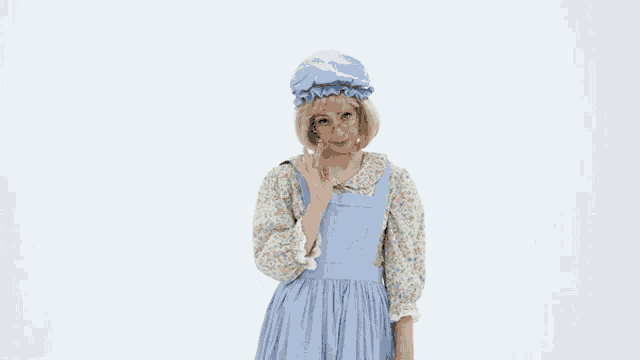 a woman in a blue dress and overalls is wearing a hat and glasses