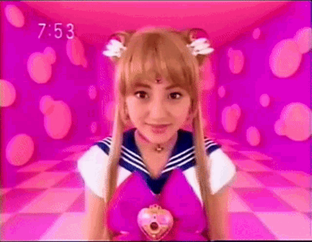 a girl in a sailor moon costume is standing in a pink room with a pink background .