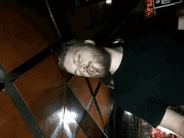 a man with a beard is sleeping in an elevator with his eyes closed and his mouth open