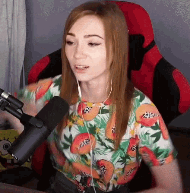 a woman is sitting in a red chair with a microphone and headphones .