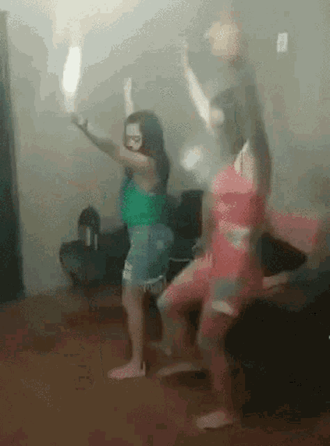 a group of women are dancing in a room with a man sitting on a couch in the background