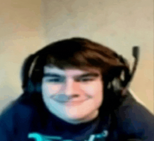 a man wearing headphones and a microphone is smiling for the camera .