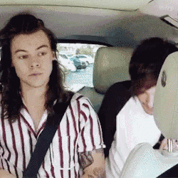 a man with long hair is sitting in the back seat of a car with a woman .
