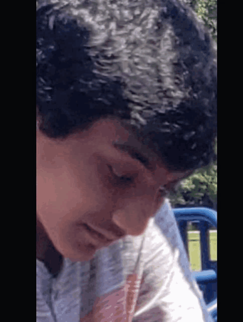 a close up of a young man 's face with a blue car in the background
