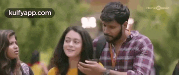 a man and a woman are standing next to each other looking at their phones .