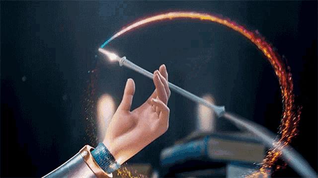 a person 's hand is holding a wand that is glowing with sparkles