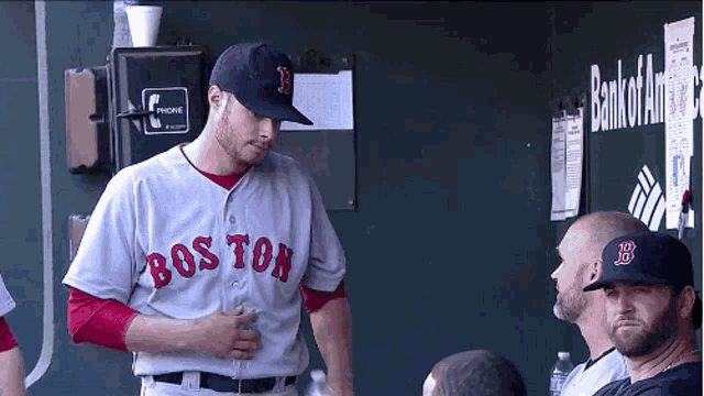 a man in a boston jersey is standing in the dugout