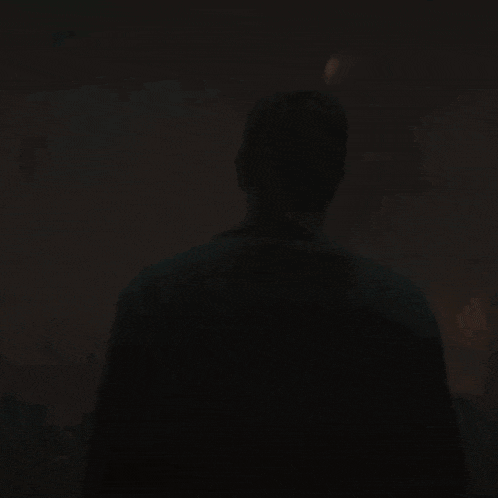 a man is standing in the dark in a dark room looking at the camera .