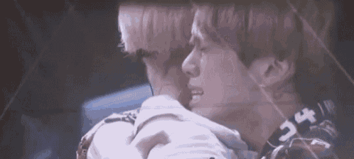 a couple of men are hugging each other in a dark room .