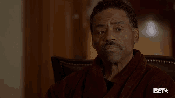 a man in a robe is sitting in a chair with the word done written on his face .