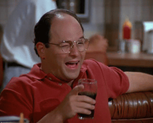 a man in a red shirt is holding a glass of soda and laughing .