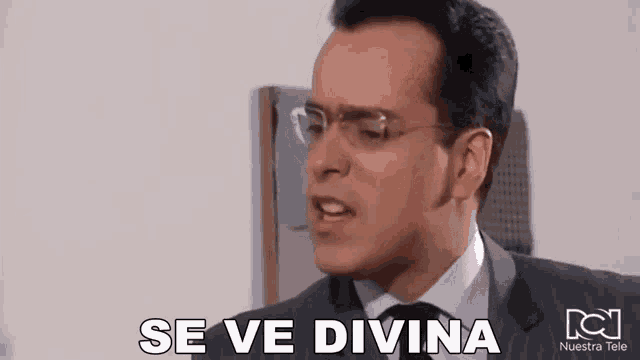 a man wearing glasses and a suit is making a funny face and saying se ve divina .