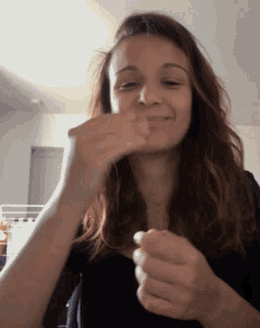 a woman with long hair is making a funny face with her hands