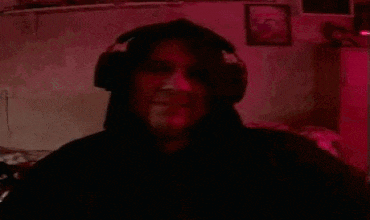 a man is wearing headphones and holding a cell phone in a dark room .