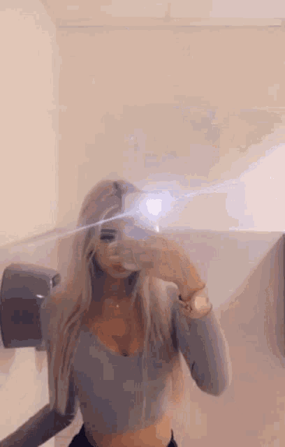 a woman is taking a selfie in a public restroom .