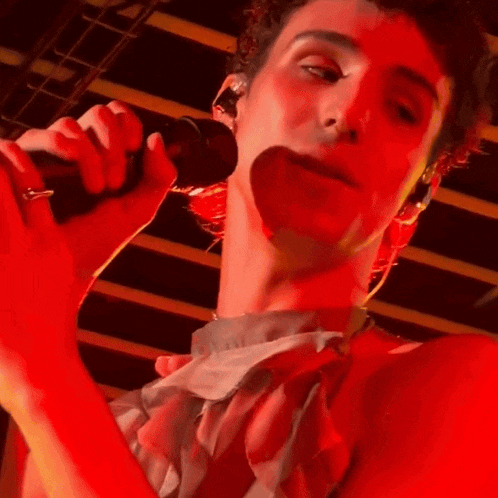 a man is singing into a microphone with a red background