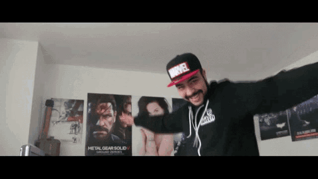 a man wearing a marvel hat is dancing in a room