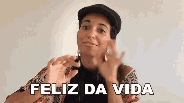 a woman wearing a hat and earrings says " feliz da vida "