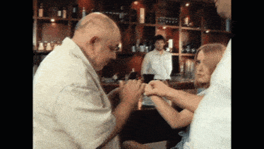 a man and a girl are holding hands in front of a bar with bottles on the shelves