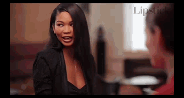 a woman in a black jacket is talking to another woman in a living room .