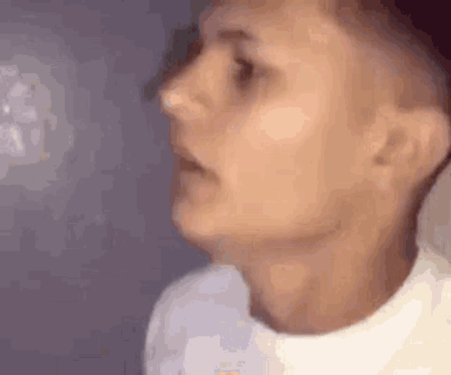 a close up of a man 's face with his mouth open and a white shirt on .