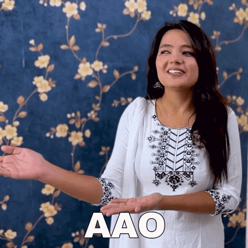 a woman in a white dress says aao in a sign language