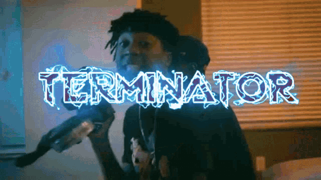 a man is holding a gun in front of a screen that says terminator