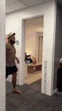 a man in a hat is walking through a doorway in an office