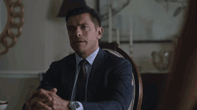 a man in a suit and tie is sitting at a table
