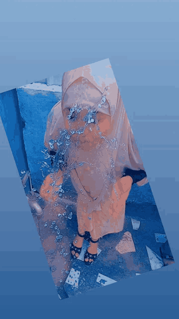 a woman in a hijab is splashing water into her face
