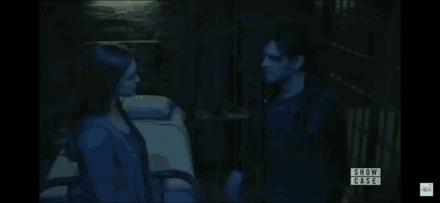 a man and a woman are standing next to each other in a dark room with the words show case on the bottom right