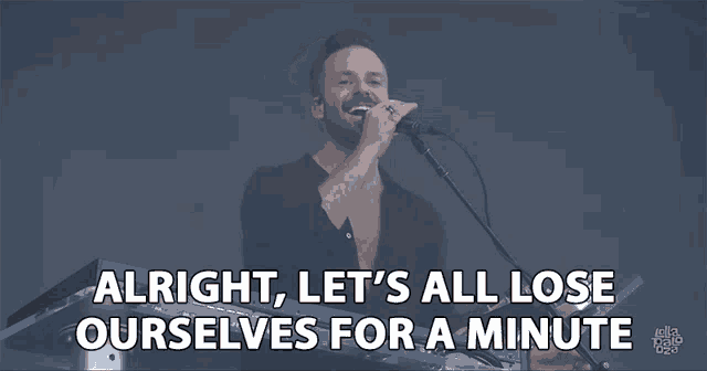 a man singing into a microphone with the words alright let 's all lose ourselves for a minute above him