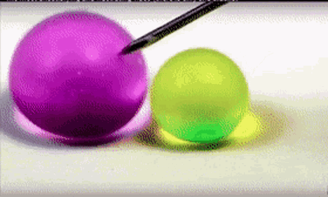 a purple and a green ball are being painted with a pencil