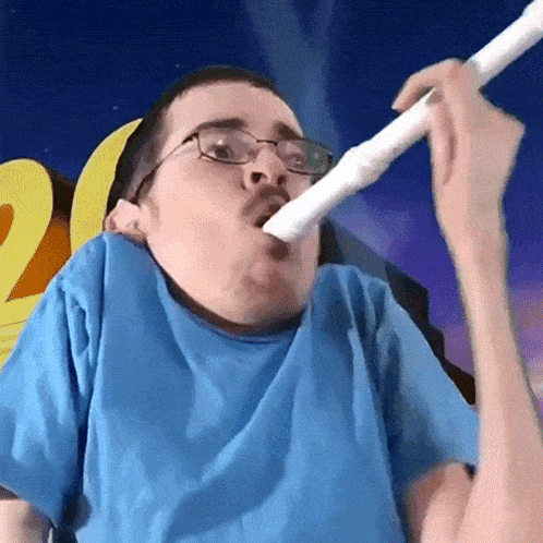 a man wearing glasses and a blue shirt is blowing into a tube