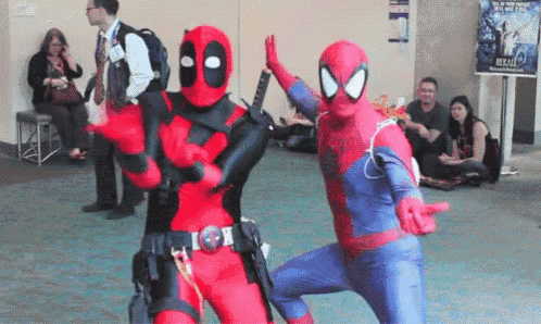 a man in a deadpool costume and a man in a spiderman costume are dancing together .