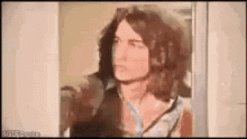 a man with long hair is standing in front of a mirror .