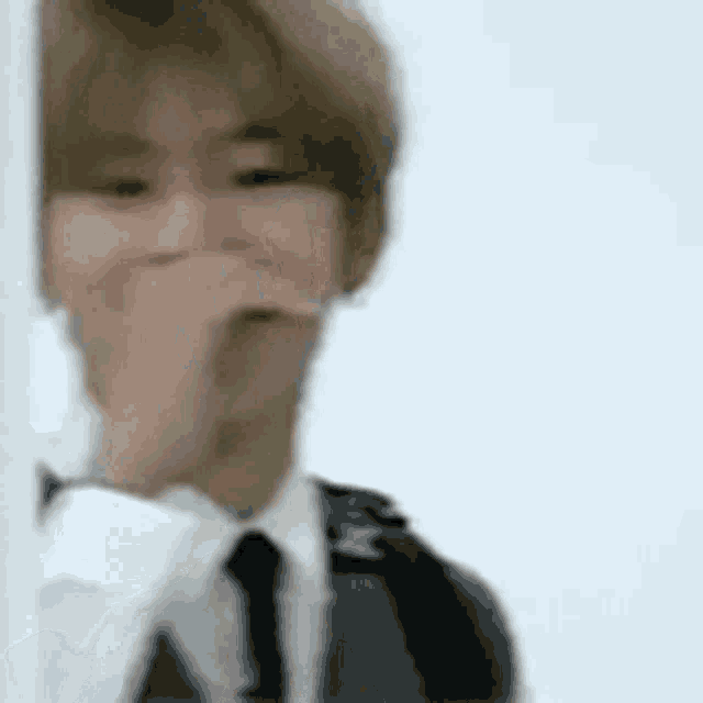 a man in a suit and tie is making a funny face while standing next to a wall .