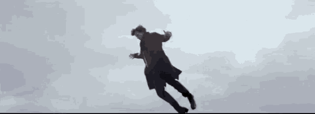 a person in a black coat is flying through a cloudy sky