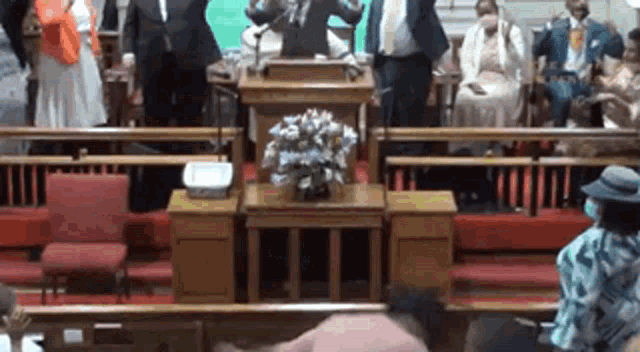 a man is standing at a podium in front of a crowd of people in a church
