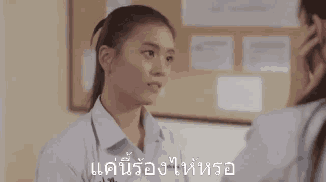 a girl in a white shirt talks to another girl in a room