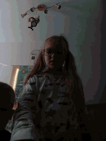 a girl wearing glasses is taking a picture of herself in a dark room