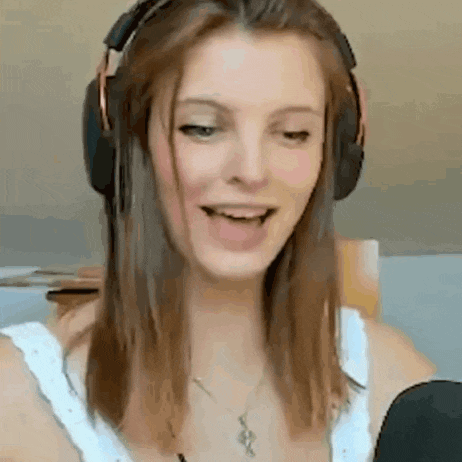 a woman wearing headphones and a necklace is talking into a microphone and smiling .