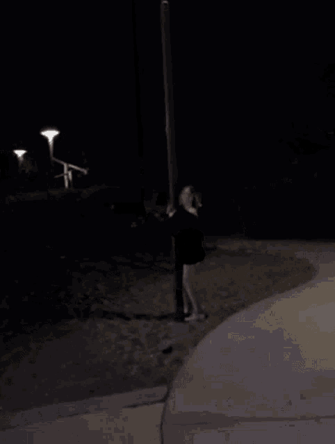 a woman is swinging on a rope swing at night