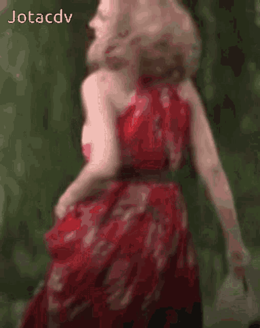 a blurry picture of a woman in a red dress with jotacdv written in the corner