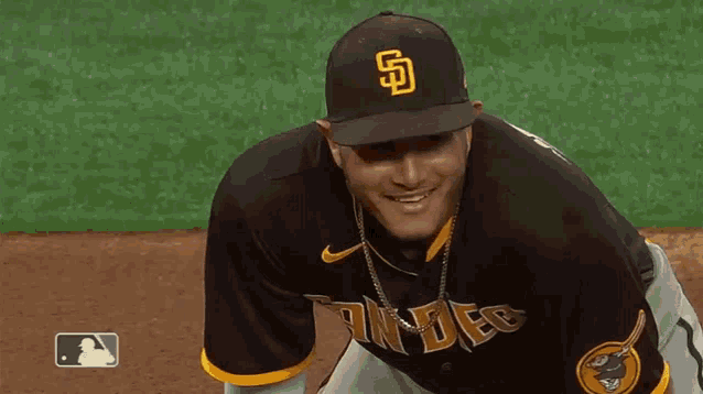 a man wearing a san diego padres baseball uniform is smiling on the field .