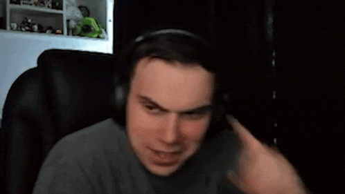 a man wearing headphones is giving a thumbs up sign while sitting in a chair .