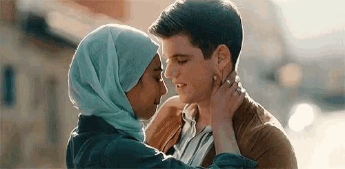 a man and a woman are kissing in front of a building .
