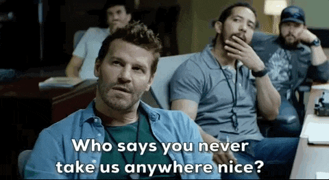 a man in a blue shirt is sitting in a chair and talking to another man .