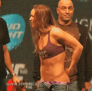 a woman in a purple ufc bra stands next to a man in a brown shirt