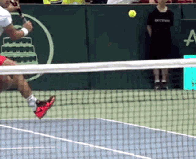 a tennis player swings a racket at a tennis ball on a court